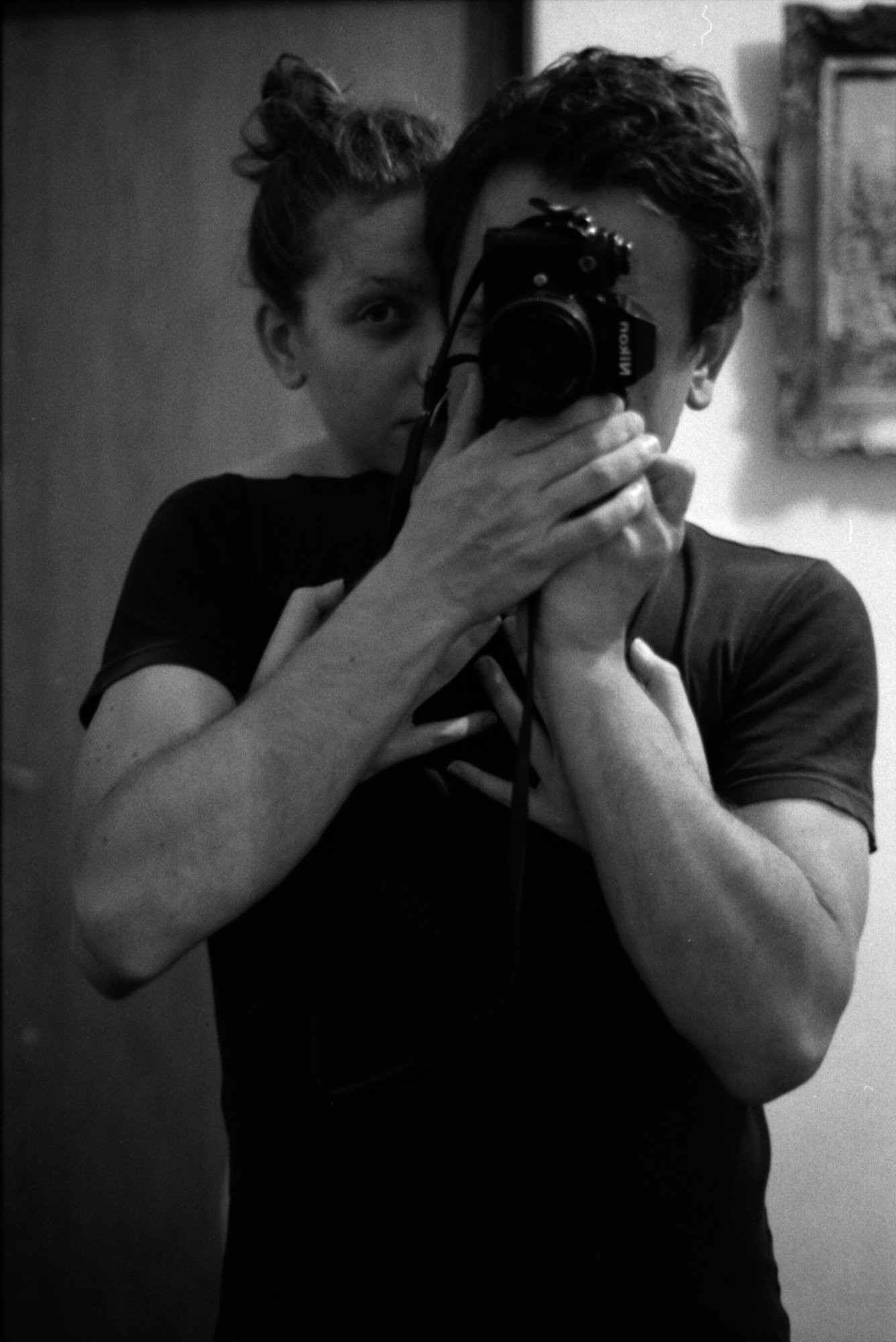 Self-portrait: the photographer holding a camera to his face, black and white.