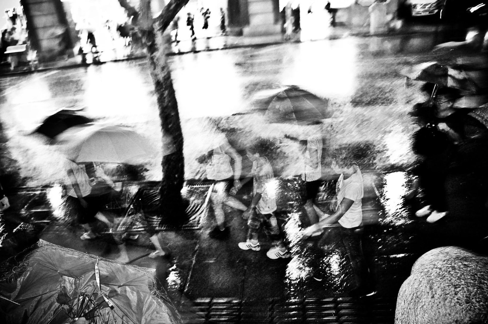 A crowded night market under umbrellas, high contrast, figures dissolving into black.