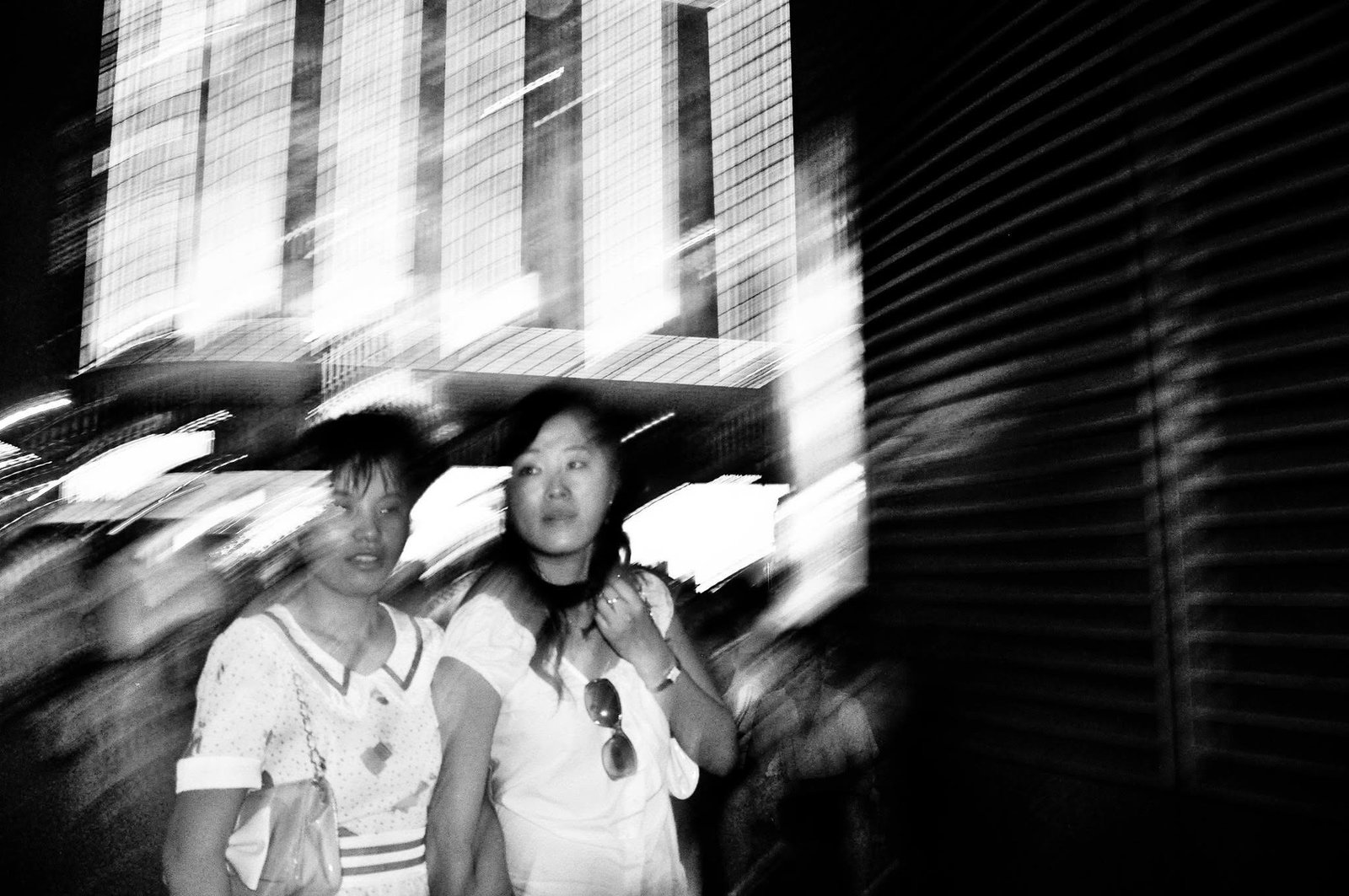 Two people sheltering under an umbrella, the city smeared by camera movement.