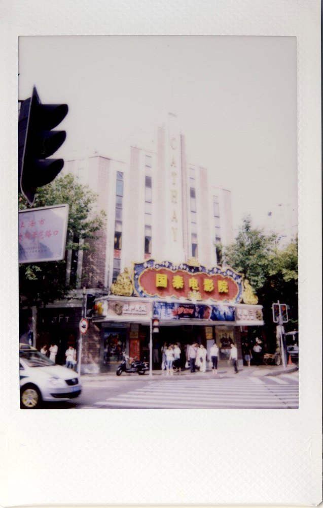 The Cathay Theatre on instant film, its art deco tower and red neon sign above a crossing.