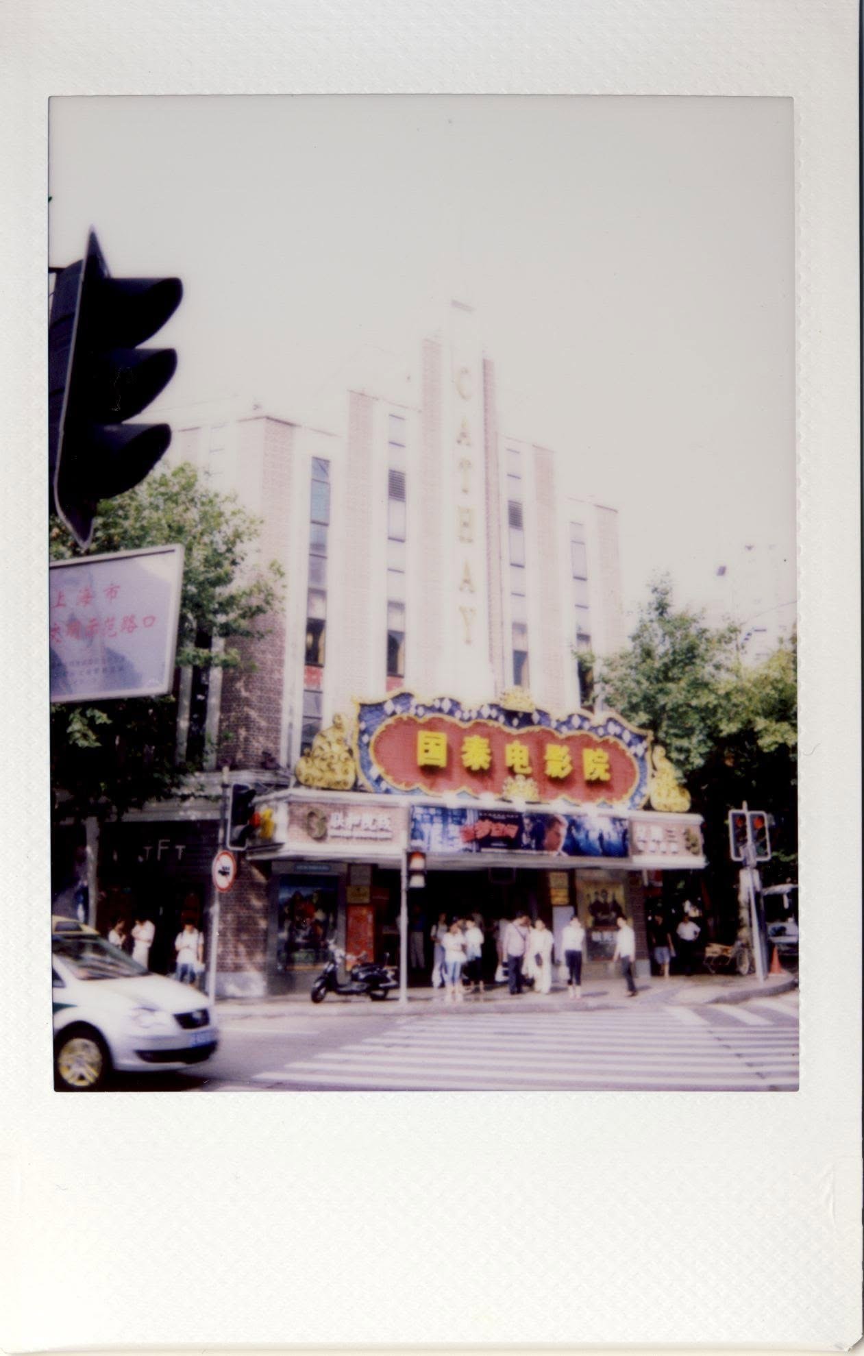 The Cathay Theatre on instant film, its art deco tower and red neon sign above a crossing.